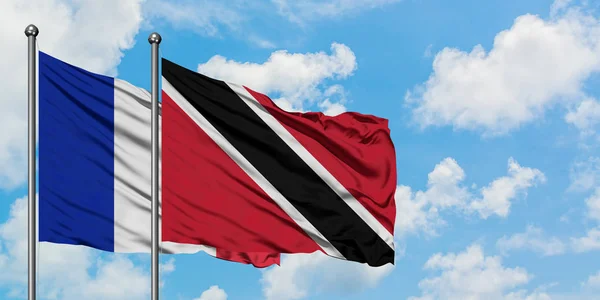 Frankrijk en Trinidad en Tobago vlag zwaaien in de wind tegen witte bewolkte blauwe hemel samen. Diplomatie concept, internationale betrekkingen. — Stockfoto