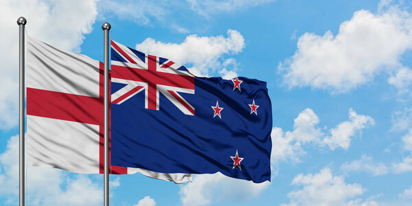 England and New Zealand flag waving in the wind against white cloudy blue sky together. Diplomacy concept, international relations.