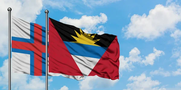 Islas Feroe y Antigua y Barbuda bandera ondeando en el viento contra el cielo azul nublado blanco juntos. Concepto diplomático, relaciones internacionales . — Foto de Stock