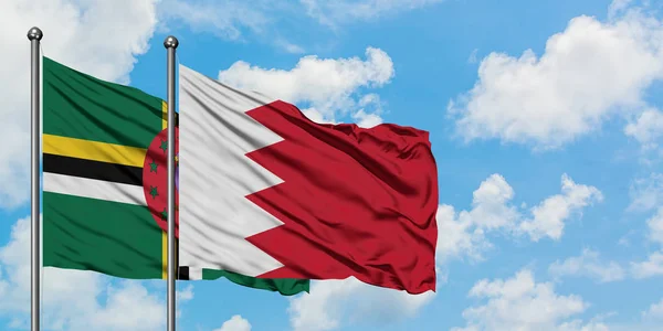 Bandera de Dominica y Bahréin ondeando en el viento contra el cielo azul nublado blanco juntos. Concepto diplomático, relaciones internacionales . — Foto de Stock