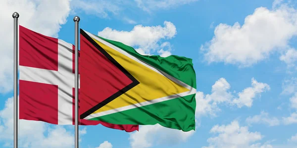 Dánia és Guyana zászló integetett a szél ellen, fehér felhős kék ég együtt. Diplomáciai koncepció, nemzetközi kapcsolatok. — Stock Fotó