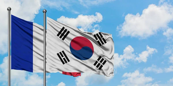 Fransa ve Güney Kore bayrağı birlikte beyaz bulutlu mavi gökyüzüne karşı rüzgarsal sallayarak. Diplomasi kavramı, uluslararası ilişkiler. — Stok fotoğraf
