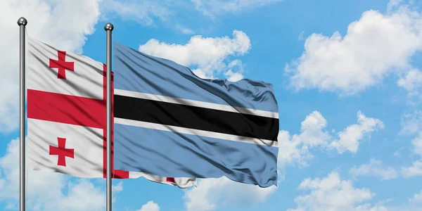 Georgia e Botswana sventolano nel vento contro il bianco cielo blu nuvoloso insieme. Concetto di diplomazia, relazioni internazionali . — Foto Stock