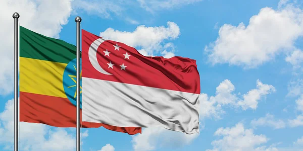 Bandera de Etiopía y Singapur ondeando en el viento contra el cielo azul nublado blanco juntos. Concepto diplomático, relaciones internacionales . — Foto de Stock