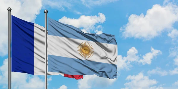 Bandera de Francia y Argentina ondeando en el viento contra el cielo azul nublado blanco juntos. Concepto diplomático, relaciones internacionales . — Foto de Stock