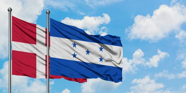 A bandeira da Dinamarca e Honduras agitando no vento contra o céu azul nublado branco juntos. Conceito de diplomacia, relações internacionais . — Fotografia de Stock