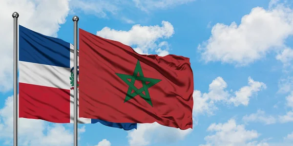 Bandera de República Dominicana y Marruecos ondeando en el viento contra el cielo azul nublado blanco juntos. Concepto diplomático, relaciones internacionales . — Foto de Stock