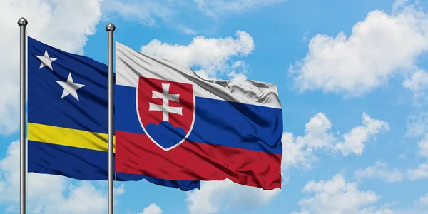 Curacao och Slovakien flagga vifta i vinden mot vit grumlig blå himmel tillsammans. Diplomatisk koncept, internationella relationer. — Stockfoto