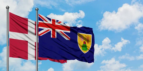 Bandera de Dinamarca y las Islas Turcas y Caicos ondeando en el viento contra el cielo azul nublado blanco juntos. Concepto diplomático, relaciones internacionales . —  Fotos de Stock