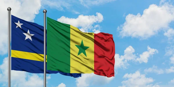 Bandera de Curazao y Senegal ondeando en el viento contra el cielo azul nublado blanco juntos. Concepto diplomático, relaciones internacionales . — Foto de Stock