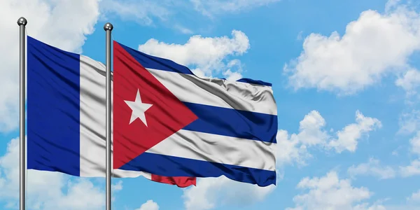 Francja i Kuba flaga machając w wiatr przed białym zachmurzone błękitne niebo razem. Koncepcja dyplomacji, stosunki międzynarodowe. — Zdjęcie stockowe