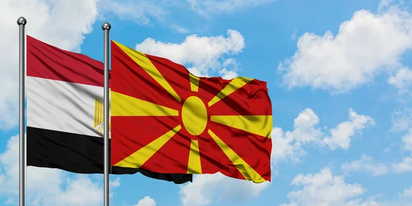 Bandera de Egipto y Macedonia ondeando en el viento contra el cielo azul nublado blanco juntos. Concepto diplomático, relaciones internacionales . — Foto de Stock