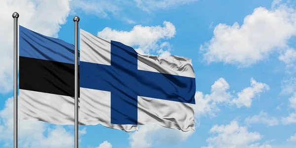 Estonia e Finlandia bandiera sventolando nel vento contro bianco cielo blu nuvoloso insieme. Concetto di diplomazia, relazioni internazionali . — Foto Stock
