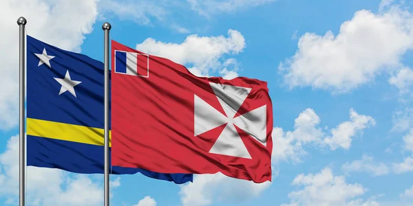 Curazao y Wallis y la bandera de Futuna ondeando en el viento contra el cielo azul nublado blanco juntos. Concepto diplomático, relaciones internacionales . — Foto de Stock