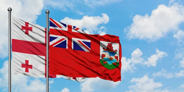 Georgië en Bermuda vlag zwaaien in de wind tegen witte bewolkte blauwe hemel samen. Diplomatie concept, internationale betrekkingen. — Stockfoto