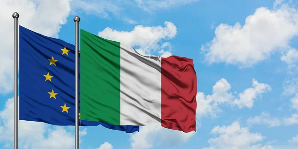 Bandera de la Unión Europea e Italia ondeando en el viento contra el cielo azul nublado blanco juntos. Concepto diplomático, relaciones internacionales . — Foto de Stock