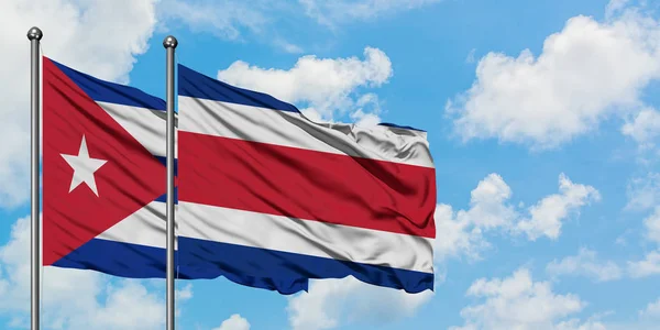 Bandera de Cuba y Costa Rica ondeando en el viento contra el cielo azul nublado blanco juntos. Concepto diplomático, relaciones internacionales . — Foto de Stock