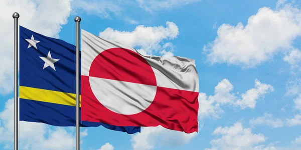 Curazao y la bandera de Groenlandia ondeando en el viento contra el cielo azul nublado blanco juntos. Concepto diplomático, relaciones internacionales . —  Fotos de Stock