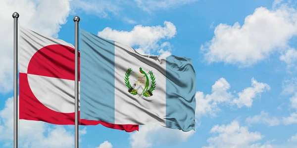 Groenlandia e Guatemala sventolano nel vento contro il bianco cielo blu nuvoloso insieme. Concetto di diplomazia, relazioni internazionali . — Foto Stock