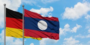 Almanya ve Laos bayrağı birlikte beyaz bulutlu mavi gökyüzüne karşı rüzgarda sallayarak. Diplomasi kavramı, uluslararası ilişkiler.