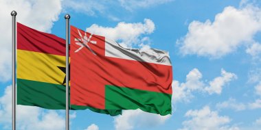 Gana ve Umman bayrağı birlikte beyaz bulutlu mavi gökyüzüne karşı rüzgarda sallayarak. Diplomasi kavramı, uluslararası ilişkiler.