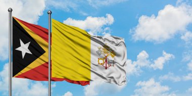 Doğu Timor ve Vatikan bayrağı birlikte beyaz bulutlu mavi gökyüzüne karşı rüzgarda sallayarak. Diplomasi kavramı, uluslararası ilişkiler.