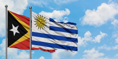 Doğu Timor ve Uruguay bayrağı birlikte beyaz bulutlu mavi gökyüzüne karşı rüzgarsal sallayarak. Diplomasi kavramı, uluslararası ilişkiler.