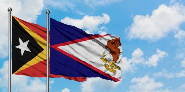 Doğu Timor ve Amerikan Samoası bayrağı birlikte beyaz bulutlu mavi gökyüzüne karşı rüzgarda sallayarak. Diplomasi kavramı, uluslararası ilişkiler.