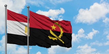 Mısır ve Angola bayrağı birlikte beyaz bulutlu mavi gökyüzüne karşı rüzgarsal sallayarak. Diplomasi kavramı, uluslararası ilişkiler.