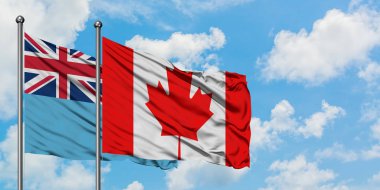 Fiji ve Kanada bayrağı birlikte beyaz bulutlu mavi gökyüzüne karşı rüzgarda sallayarak. Diplomasi kavramı, uluslararası ilişkiler.