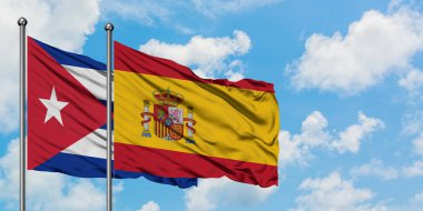 Küba ve İspanya bayrağı birlikte beyaz bulutlu mavi gökyüzüne karşı rüzgarsal sallayarak. Diplomasi kavramı, uluslararası ilişkiler.