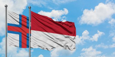 Faroe Adaları ve Monako bayrağı birlikte beyaz bulutlu mavi gökyüzüne karşı rüzgarda sallayarak. Diplomasi kavramı, uluslararası ilişkiler.