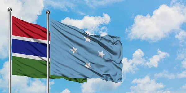 Gambia und Mikronesien schwenken gemeinsam die Flagge im Wind gegen den wolkenverhangenen blauen Himmel. Diplomatie-Konzept, internationale Beziehungen. — Stockfoto