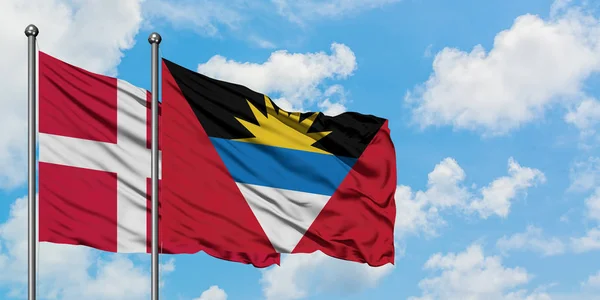 Dania i Antigua i Barbuda flaga machając w wiatr przed białym pochmurno błękitne niebo razem. Koncepcja dyplomacji, stosunki międzynarodowe. — Zdjęcie stockowe