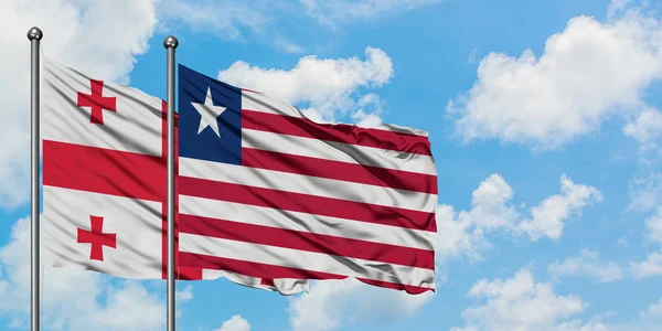 Gruzja i Liberia flaga machając w wiatr przed białym zachmurzone błękitne niebo razem. Koncepcja dyplomacji, stosunki międzynarodowe. — Zdjęcie stockowe