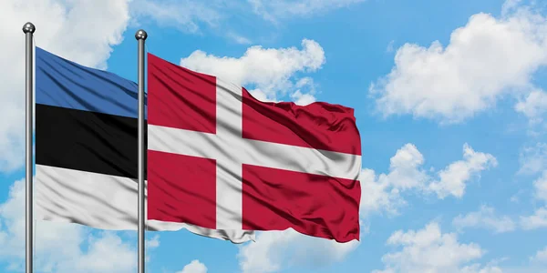 一緒に白い曇り青い空に対して風に振るエストニアとデンマークの旗。外交概念、国際関係. — ストック写真