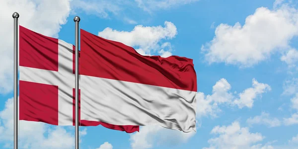 Dánsko a Indonésie vlají ve větru proti bíle zatažené modré obloze. Diplomacie, mezinárodní vztahy. — Stock fotografie