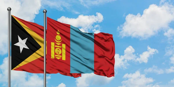 Timor Wschodni i Mongolia flaga machając w wiatr przed białym zachmurzone błękitne niebo razem. Koncepcja dyplomacji, stosunki międzynarodowe. — Zdjęcie stockowe