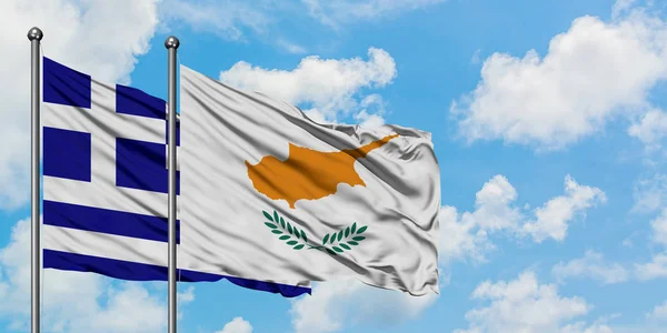 Griechenland und Zypern schwenken gemeinsam die Flagge im Wind vor dem wolkenverhangenen blauen Himmel. Diplomatie-Konzept, internationale Beziehungen. — Stockfoto