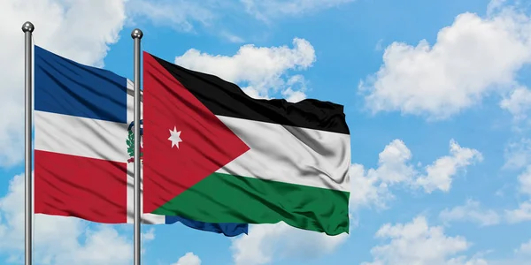 Bandera de República Dominicana y Jordania ondeando en el viento contra el cielo azul nublado blanco juntos. Concepto diplomático, relaciones internacionales . — Foto de Stock