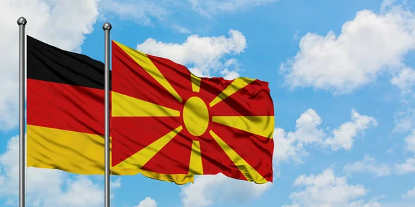 Duitsland en Macedonië vlag zwaaien in de wind tegen witte bewolkte blauwe hemel samen. Diplomatie concept, internationale betrekkingen. — Stockfoto