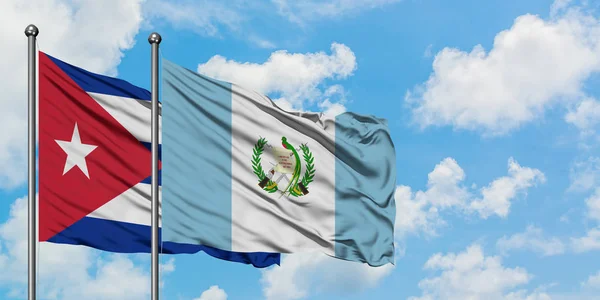 Cuba e a bandeira da Guatemala agitando no vento contra o céu azul nublado branco juntos. Conceito de diplomacia, relações internacionais . — Fotografia de Stock