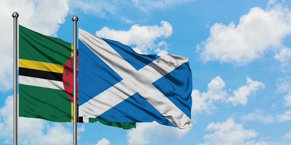 Dominica and Scotland flag waving in the wind against white cloudy blue sky together. Diplomacy concept, international relations.