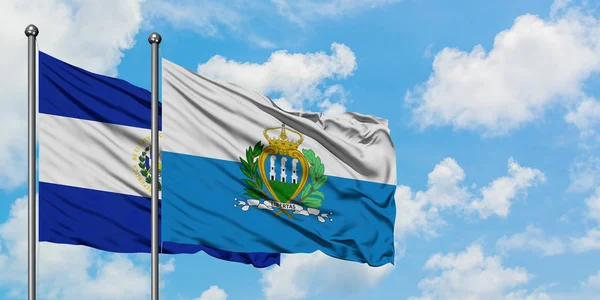 Bandera de El Salvador y San Marino ondeando en el viento contra el cielo azul nublado blanco juntos. Concepto diplomático, relaciones internacionales . — Foto de Stock