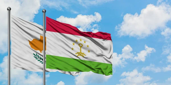Bandera de Chipre y Tayikistán ondeando en el viento contra el cielo azul nublado blanco juntos. Concepto diplomático, relaciones internacionales . — Foto de Stock