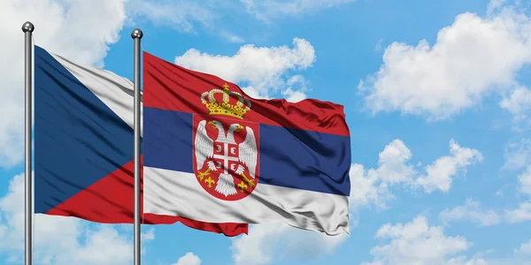Bandera de la República Checa y Serbia ondeando en el viento contra el cielo azul nublado blanco juntos. Concepto diplomático, relaciones internacionales . — Foto de Stock