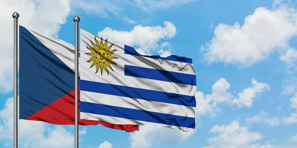 Bandera de República Checa y Uruguay ondeando en el viento contra el cielo azul nublado blanco juntos. Concepto diplomático, relaciones internacionales . — Foto de Stock