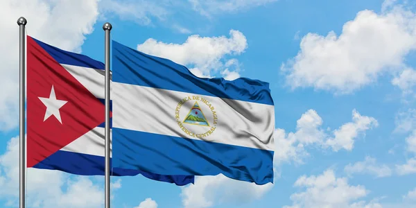 Cuba et le Nicaragua drapeau agitant dans le vent contre ciel bleu nuageux blanc ensemble. Concept de diplomatie, relations internationales . — Photo