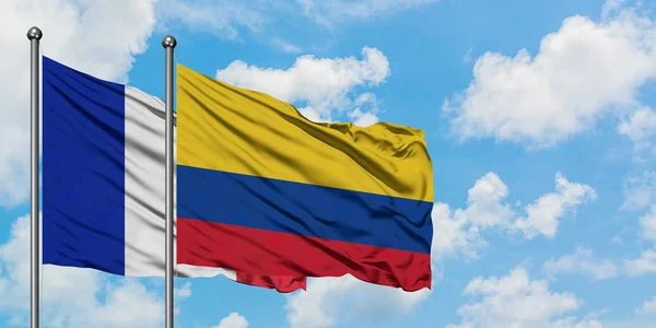 Bandera de Francia y Colombia ondeando en el viento contra el cielo azul nublado blanco juntos. Concepto diplomático, relaciones internacionales . — Foto de Stock