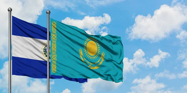 Bandera de El Salvador y Kazajstán ondeando en el viento contra el cielo azul nublado blanco juntos. Concepto diplomático, relaciones internacionales . — Foto de Stock